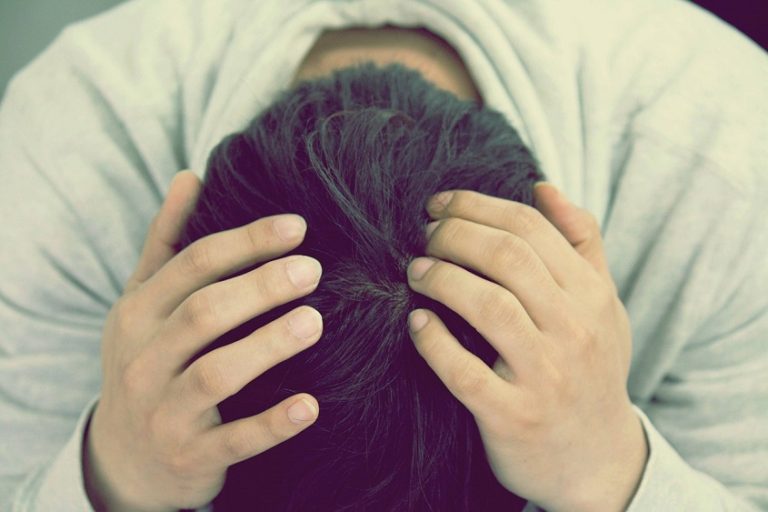 A person sitting alone with their head in their hands