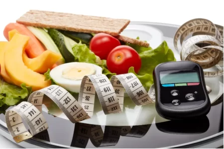 a plate of food with measuring tape and a glucometer