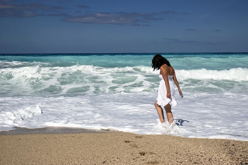 A woman in a white dress walking in the water