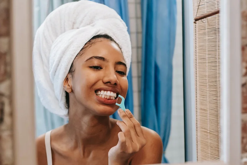 woman cleaning teeth with dental floss