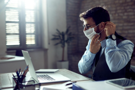 Employee sitting at desk looking fatigued due to health condition, considering medical leave from work.