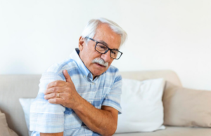 Old person holding shoulder in pain after a fall, indicating possible rotator cuff tear or dislocation.