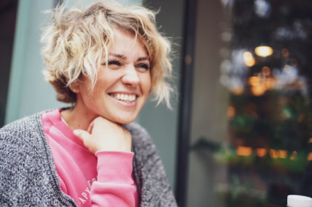 Smiling healthy woman practicing healthy lifestyle habits including hydration, fitness, sleep, and self-care for overall wellness