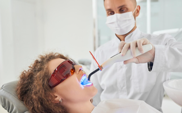a doctor is providing dental whitening procedure to a lady in clinic