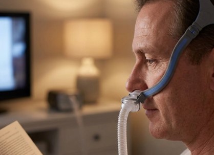 Person working comfortably while wearing a nasal pillow CPAP mask for sleep apnea therapy.