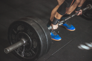 How to Break a Training Plateau and Start Progressing Again Gym athlete lifting weights while tracking workout progress to overcome a training plateau and improve strength.