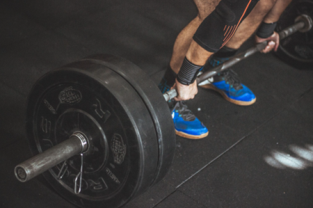How to Break a Training Plateau and Start Progressing Again Gym athlete lifting weights while tracking workout progress to overcome a training plateau and improve strength.