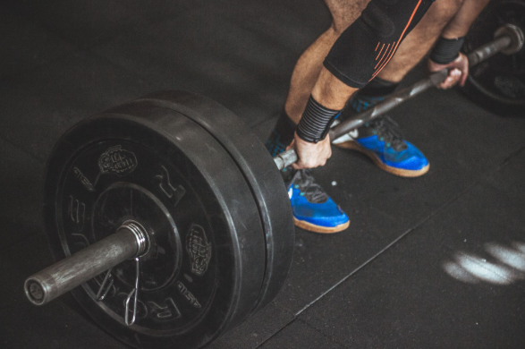 Gym athlete lifting weights while tracking workout progress to overcome a training plateau and improve strength.