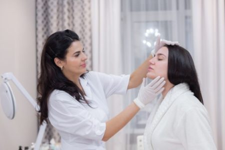 Facial plastic surgeon discussing facial rejuvenation treatment options with a patient.