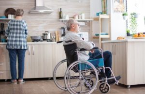 Person with Parkinson's disease using a wheelchair with caregiver assistance at home