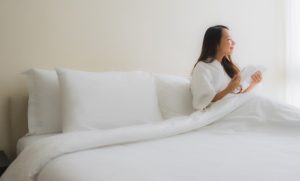 Person sitting comfortably on a firm mattress with proper spinal alignment in a modern bedroom.