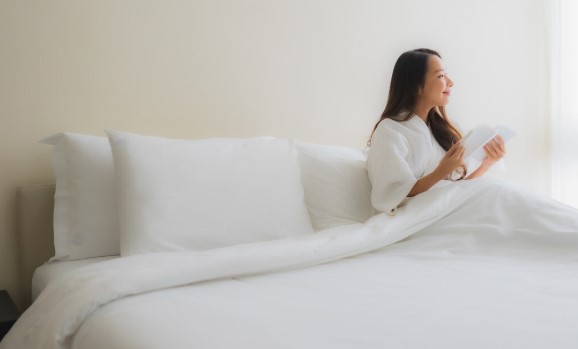 Person sitting comfortably on a firm mattress with proper spinal alignment in a modern bedroom.