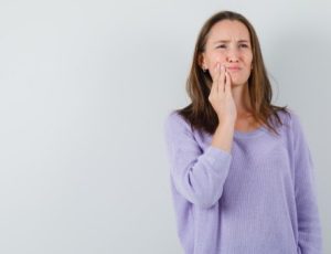 Young female suffering from toothache due to gum disease