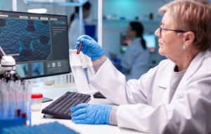 Scientist analyzing raw DNA sequencing data on a computer for genetic variant interpretation.