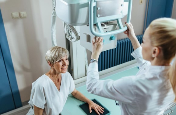 Radiographer preparing a patient for a medical imaging scan in a diagnostic imaging department.