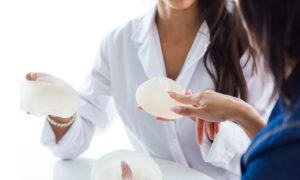 5 Questions to Ask Before Choosing Breast Reduction Surgery Woman discussing breast reduction surgery options and expected results with a plastic surgeon during a consultation.