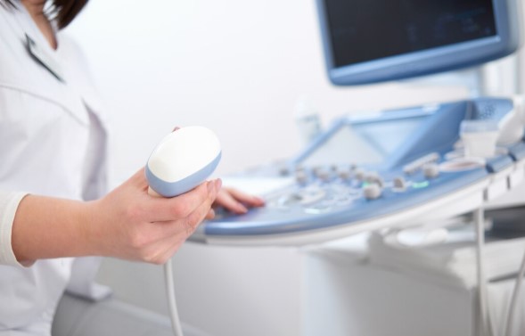 Healthcare professional performing an ultrasound examination using a transducer to create real-time diagnostic images.